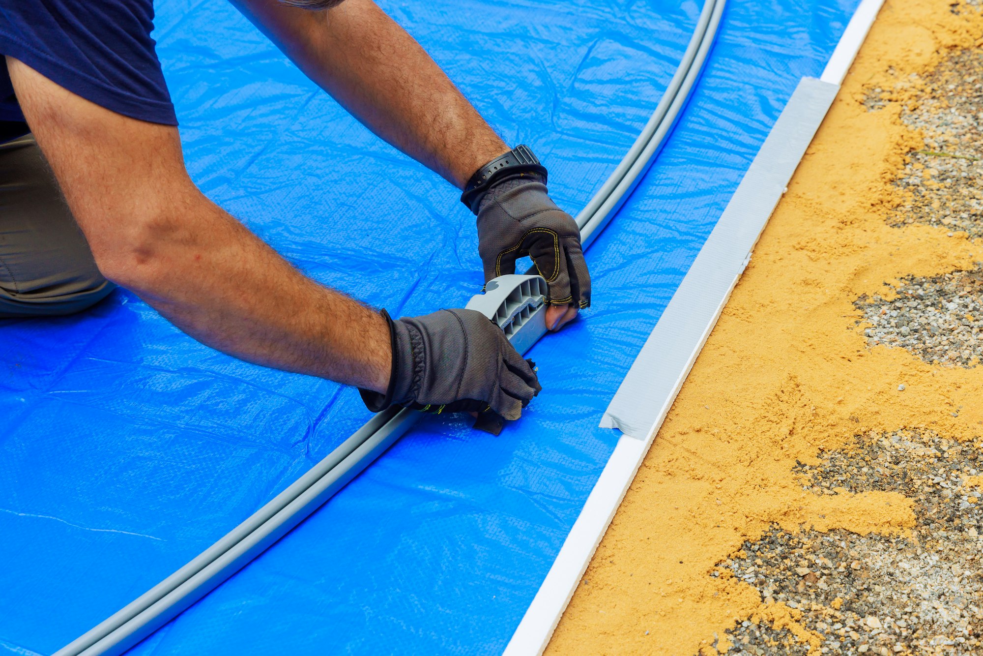 An above ground pool metal frame is being assembled by a worker