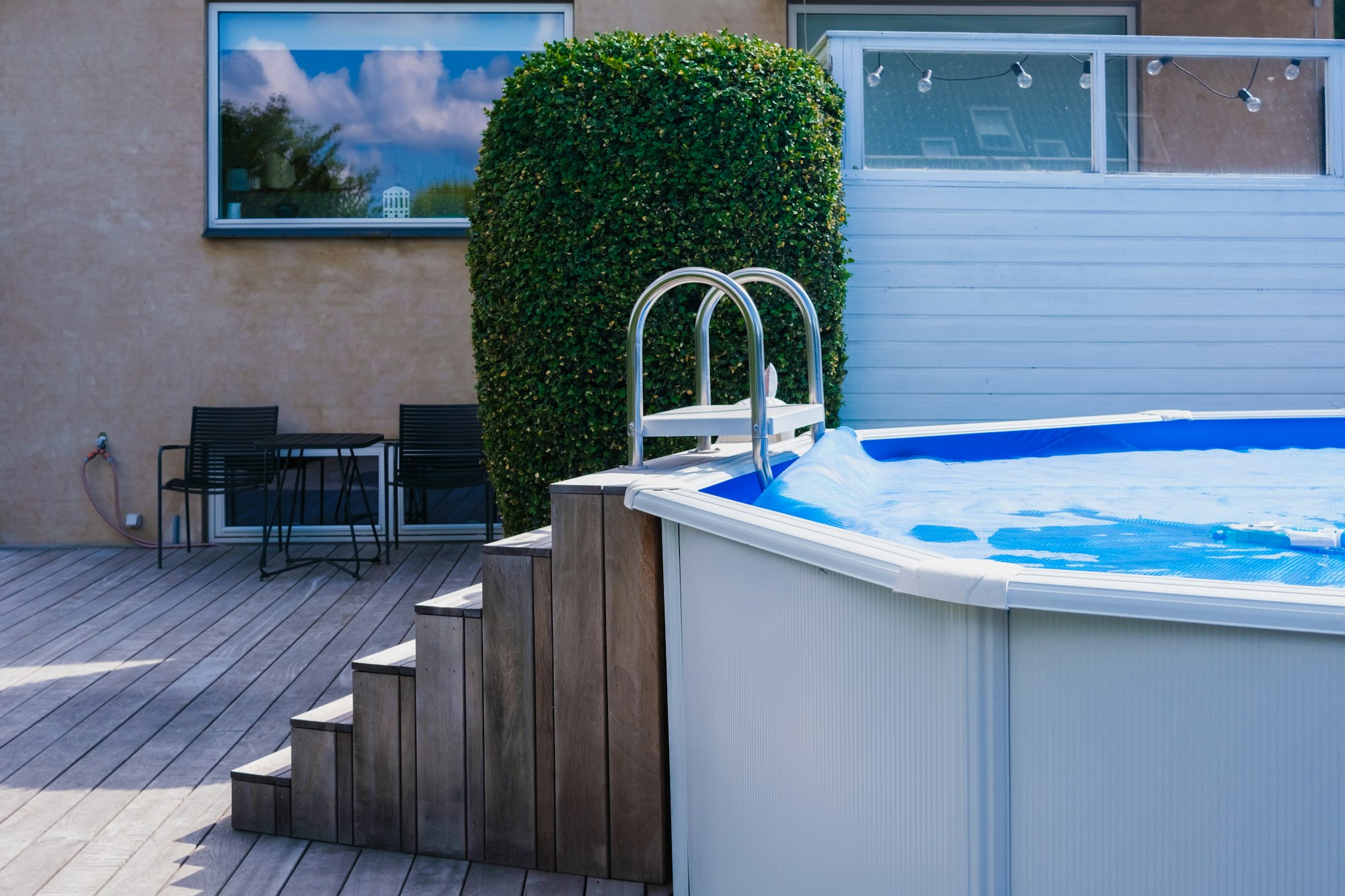 Detail of a portable pool, mounted in the backyard, decorated with wood.